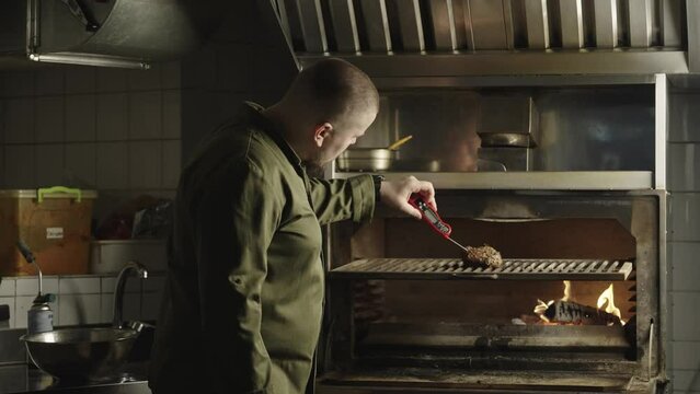 The chef checks the temperature of the meat with an electronic thermometer. Cooking steak on the grill in a professional kitchen. High quality 4k footage