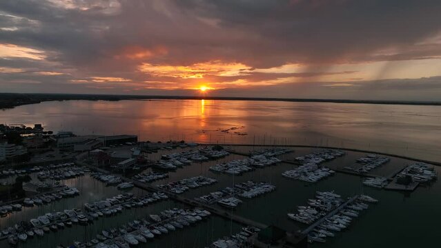 MONFALCONE, ITALY - APRIL, 2023: Sailing yacht moored off the coast Adriatic sea in Italy at sunset. Drone aerial view, cinematic frame. Romantic atmosphere. Calm and pacifying scene.