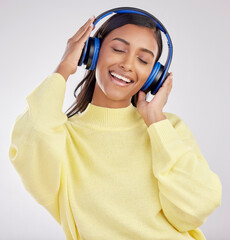 Woman with headphones, listening to music and happy on studio background with freedom, fun and...