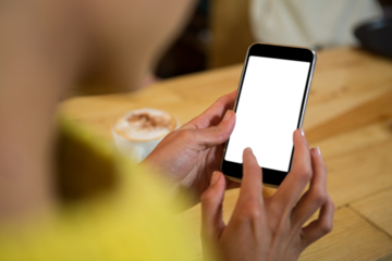 Woman using mobile phone at table in cafe
