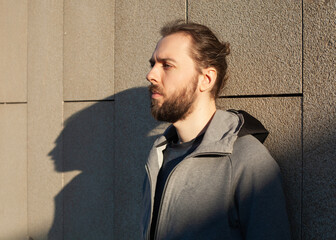 a man in sports clothes stands near the wall in the rays of sunlight