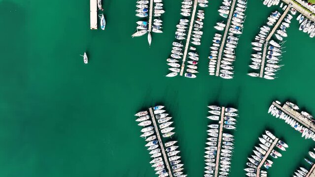 MONFALCONE, ITALY - APRIL, 2023: Sailing yacht moored off the coast Adriatic sea in Italy at sunny day. Drone aerial view, cinematic frame. Romantic atmosphere. Calm and pacifying scene.