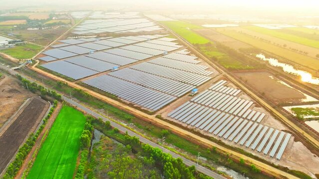 A beautiful scene from above as the sun sets, the solar power plant sprawls out with rows of shining solar panels capturing the last rays of light. Clean and renewable energy concepts. 4K Drone

