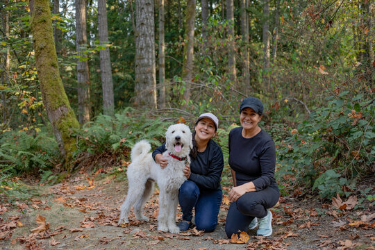 Portrait of two women with a dog in a woodland area; Vancouver Island, British Columbia, Canada