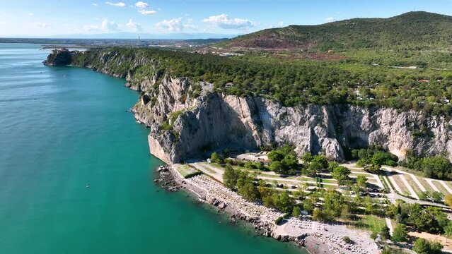 MONFALCONE, ITALY - APRIL, 2023: Sailing yacht moored off the coast Adriatic sea in Italy at sunny day. Drone aerial view, cinematic frame. Romantic atmosphere. Calm and pacifying scene.