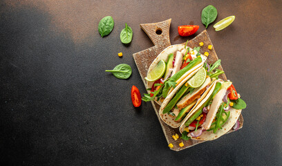 burritos tacos grilled chicken, avocado, fresh tomatoes, limes on a wooden board. Long banner...