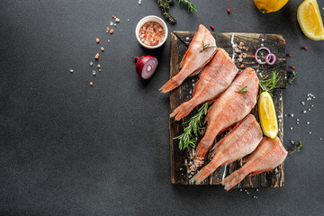 Fish raw snapper with lemon, rosemary, salt on a wooden board. banner, menu, recipe place for text, top view