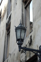 Old Black Metal Street Lamp on a Gray Concrete Wall next to an Open Window