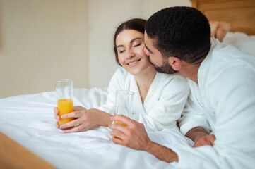 Man Kissing Woman Lying In Bed In Hotel Room Indoor
