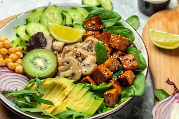 Teriyaki baked tofu with avocado, chickpeas, cucumber and mushrooms. buddha bowl. Vegan lunch salad. Food recipe background. Close up