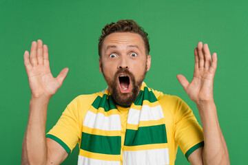 shocked sports fan in striped scarf and yellow t-shirt shouting isolated on green.