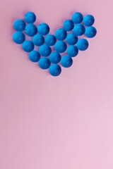 Hydrogel balls are laid out in the shape of a heart on a pink background.
