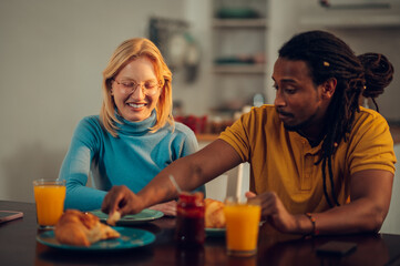 A young happy multiracial couple is eating breakfast at home.