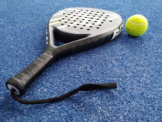 racket or shovel to play sports Padel tennis with a ball next to it on the court floor