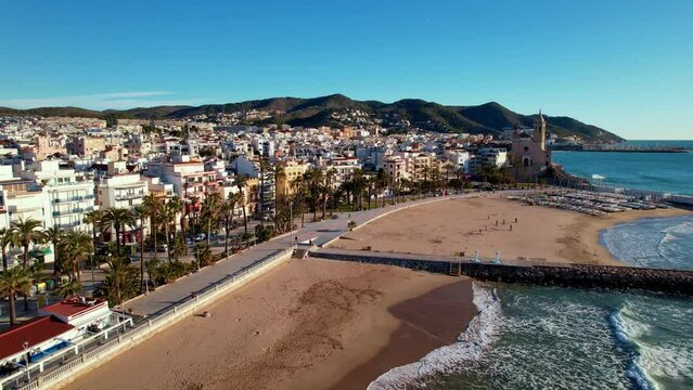 Panoramic aerial drone view of coastal village, Sant Bartomeu i Santa Tecla de Sitges during sunny day in Sitges, town near Barcelona in Catalonia, Spain. It is famous for its beaches and nightlife