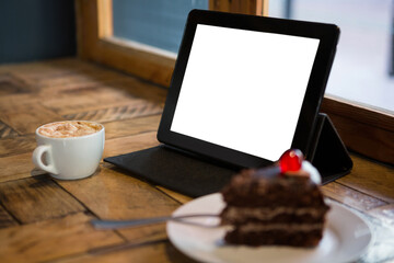 Digital tablet with pastry and coffee cup on table