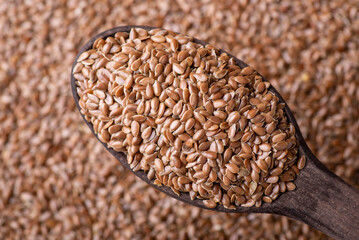 Linen grain in wooden spoon close up. Healthy food for stomach, cooking with linen grain