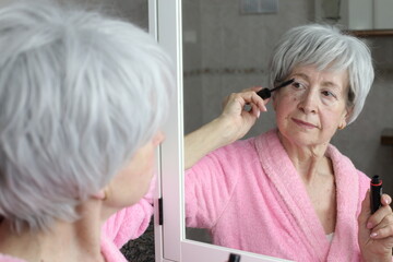 Senior woman using eye mascara 