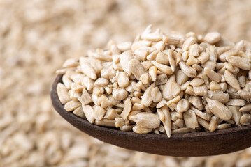 Close up of peeled sunflower grain in dark wooden spoon. Fresh harvested sunflower seeds
