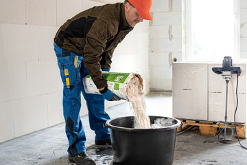 Construction work. Adding dry mortar mixture into clear water to make a mortar.