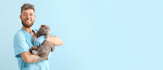 Male veterinarian with Scottish fold cat on light blue background with space for text