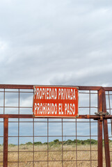 Portón de acceso a una finca con un letrero que prohíbe el acceso a una propiedad privada. Imagen vertical.