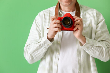 Mature photographer with professional camera on green background, closeup
