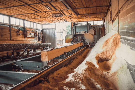 Sawmill. Process of machining logs in equipment sawmill machine saw saws the tree trunk on the plank boards. Wood sawdust work sawing timber wood wooden woodworking