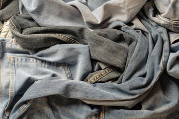 Lots of crumpled jeans pants, closeup. Denim background. The concept of buying, selling, shopping and trendy modern clothes