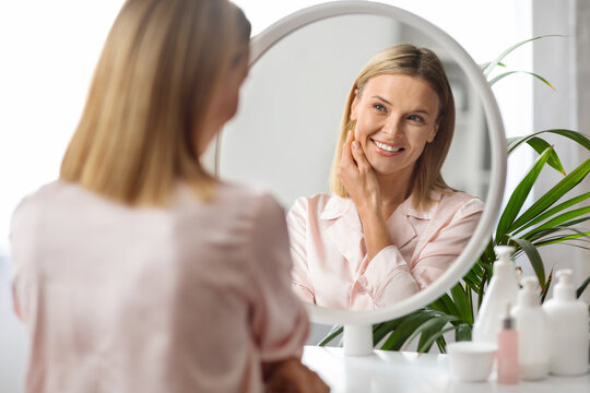 Beauty Care. Middle Aged Woman Looking In Mirror At Home And Smiling