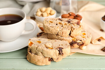 Stack of tasty biscotti cookies and cup of coffee on color wooden table, closeup