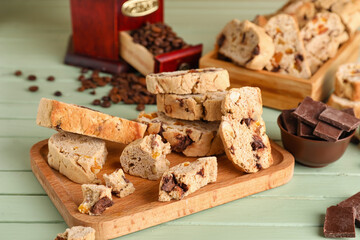 Board with tasty biscotti cookies and chocolate on color wooden background