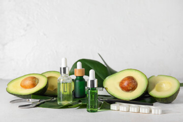 Composition with bottles of cuticle oil, manicure instruments, avocado and palm leaf on light background
