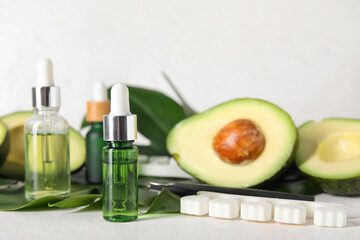 Composition with bottles of cuticle oil, manicure instruments, avocado and palm leaf on light background, closeup