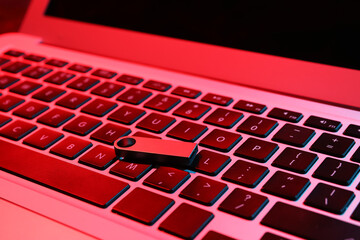 Metallic USB flash drive on modern laptop, closeup