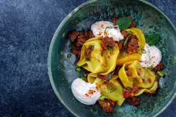 Traditional oriental manti dumplings with spicy minced meat and yogurt served as top view in a...