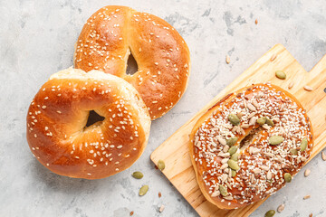 Wooden board of tasty bagels with sesame and pumpkin seeds on grunge background