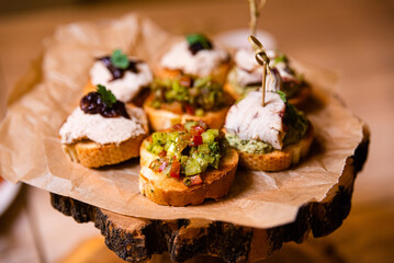 variety of bruschettas with turkey meat, diced vegetables, tuna spread and caramelized onion on a wooden board