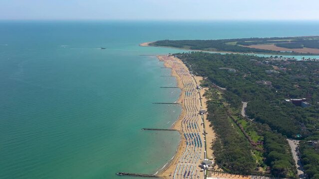 LIGNANO, ITALY - APRIL, 2023: Lignano beach at Adriatic sea coastline in Italy, Europe during summer. Sun loungers and umbrellas by the sea from above.