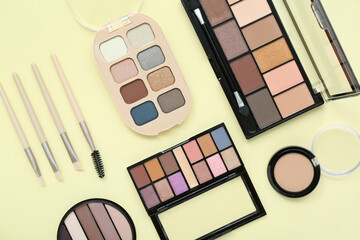 Eyeshadows with brushes on yellow background