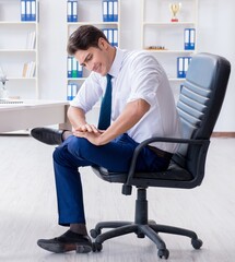 Young businessman doing sports stretching at workplace