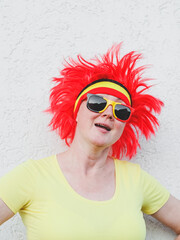 Portrait of a caucasian blonde woman with a Belgian flag wig with red hair and sunglasses