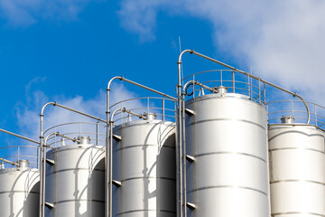 Stainless steel silos against the blue sky. Warehouses for storage of plastics and bulk grains.