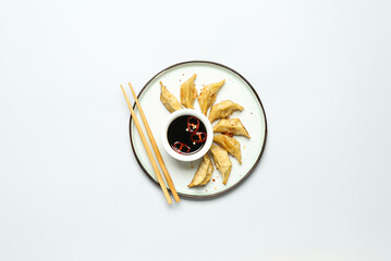 Plate with tasty Chinese jiaozi and sauce on white background
