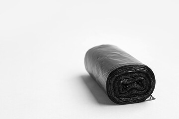 Black roll of garbage bags on grey background