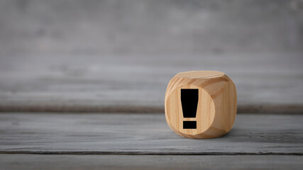 Business  design concept. Abstract geometric wooden dice isolate with an exclamation mark icon  on white rustic surface.