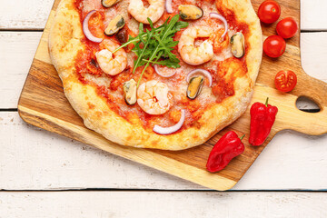 Board with tasty seafood pizza on light wooden background, closeup