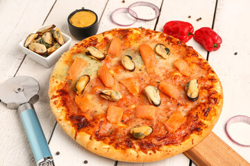 Board with tasty seafood pizza on light wooden background