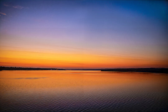 Minimalist Sunset over the lake with reflections in water and a few lights visible on far shore