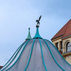 The dome of the gazebo against the blue sky. The silhouette of a bird in flight.